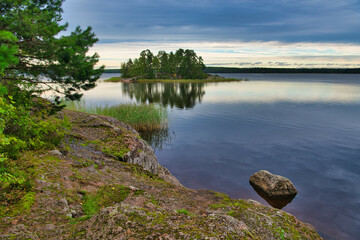Fototapeta na wymiar Island with pine forest in beautiful fresh blue lake, Park Mon Repos, Vyborg, Russia