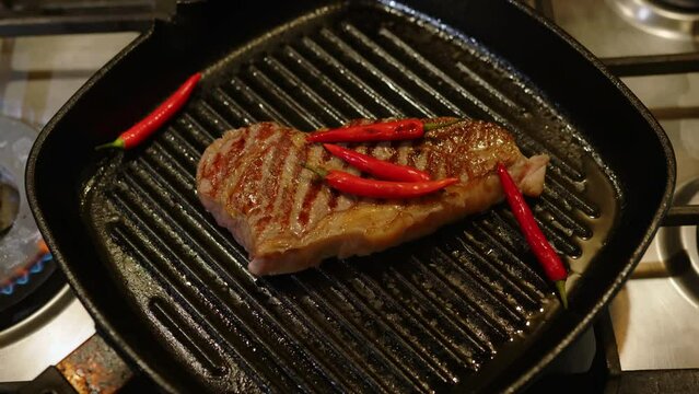 Cooking beef steak on grill frying pan with hot pepper medium rare roast.