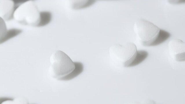 Macro white heart shape drugs, closeup medical pills falling, medicine concept