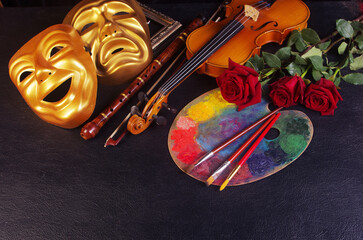 Theatre, music, painting, art attributes. Theatrical masks, violin, bow, pipe, art palette, brushes, red roses on a black background.