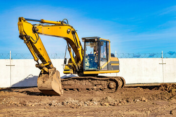 Fototapeta na wymiar Yellow crawler excavator at the construction site. Earthworks at a construction site. Modern earthmoving equipment.