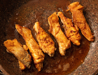 The fish is fried in a frying pan in oil. Close-up.