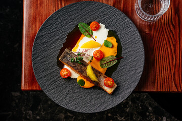 grilled salmon steak with sauce in a plate on a wooden table