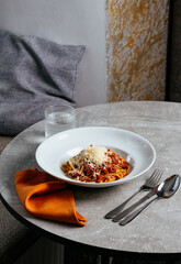 pasta bolognese in a white plate on a light table in a restauran