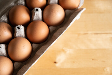 Close up of a carton of brown organic eggs on wood kitchen table