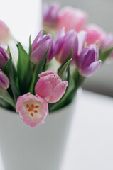 A bouquet with tulips of delicate shades in a white vase.