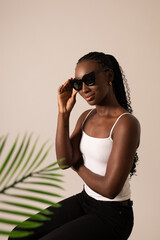 Female black model with sunglasses and a palm leaf at the studio