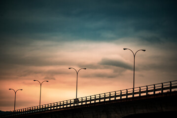 Fototapeta na wymiar Golden Gateway: Bridge Under Cloudy Sunset Sky