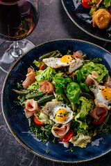 salad with quail eggs, bacon, vegetables, herbs and sauce