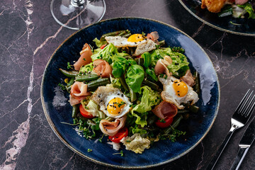 salad with quail eggs, bacon, vegetables, herbs and sauce