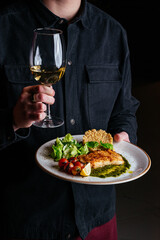 a man holds a plate of grilled fish