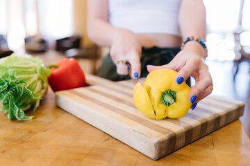 Hands with manicured nails chopping bright fresh veggies in kitchen