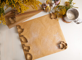 Work surface on the table in the kitchen on which baking paper with Easter cookie cutters