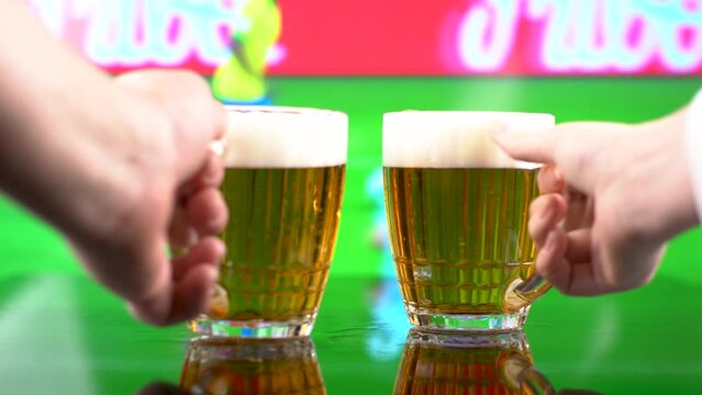 Two glasses of German light beer, beer poured into a mug, football match on TV in the background, selective focus.