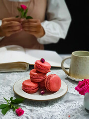 French macaroons cake. Selective focus of delicious pink macaroons with pink baby rose flowers on black background