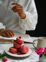 French macaroons cake. Selective focus of delicious pink macaroons with pink baby rose flowers on black background
