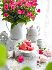 French macaroons cake. Selective focus of delicious pink macaroons with pink baby rose flowers on white background.