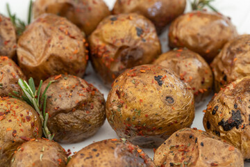 Fried (baked) whole small potatoes with rosemary and salt in a frying pan, ruddy crust, appetizing food