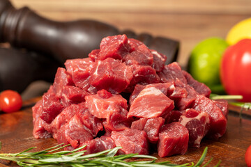 Raw fresh beef or lamb cubes. Diced red beef meat on a wood serving board. Raw casserole or stewing...