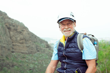 Senior hiker man with backpack and helmet enjoying trekking day on mountain - Active tourist enjoying holidays and healthy lifestyle - Freedom sport concept