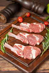 Raw lamb chops. Fresh raw lamb chops with spices and herbs. Wood background. Close up