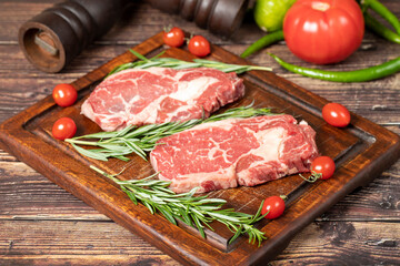 Beef ribeye. Two fresh raw ribeye steaks with spices and rosemary. Special entrecote. wood background