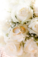 goldene Eheringe auf weißen Rosen bei Hochzeit