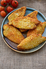 
 Crispy oven baked  chicken breast with sesame seeds and ketchup. Breaded chicken fillets  with chilly peppers and fresh basi on wooden rustic background