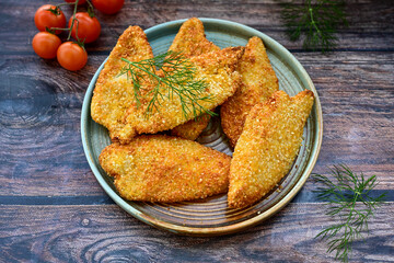 
 Crispy oven baked  chicken breast with sesame seeds and ketchup. Breaded chicken fillets  with chilly peppers and fresh basi on wooden rustic background