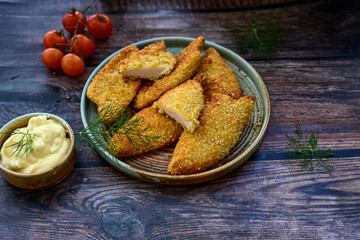 
 Crispy oven baked  chicken breast with sesame seeds and ketchup. Breaded chicken fillets  with chilly peppers and fresh basi on wooden rustic background