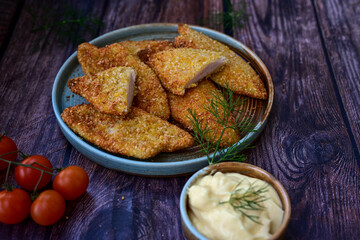 
 Crispy oven baked  chicken breast with sesame seeds and ketchup. Breaded chicken fillets  with chilly peppers and fresh basi on wooden rustic background