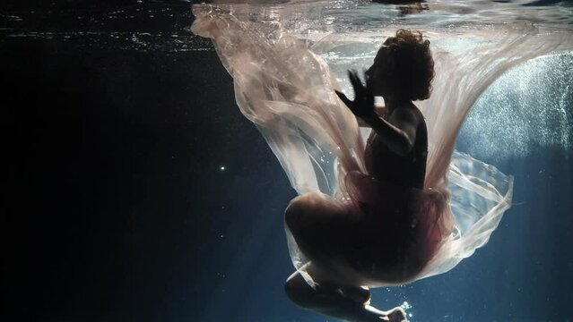 Beautiful girl in a dress underwater in a photo studio.