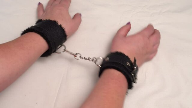 The lady is wearing black handcuffs with a soft leather lining, and they are connected by a steel chain. 