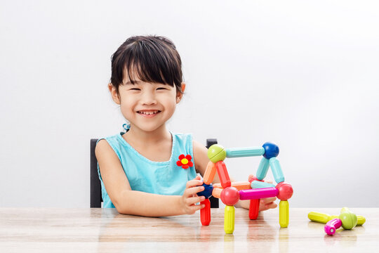 Asian girl playing colorful jigsaw puzzles in the shape of a house , stock image for advertising materials about building a house or selling a house