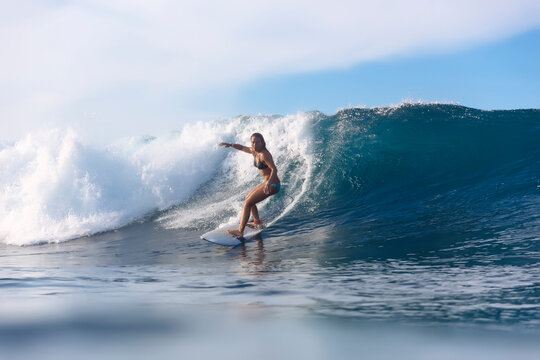 Woman surfing on sea against cloudy sky