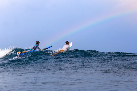 Friends surfing on sea against sky