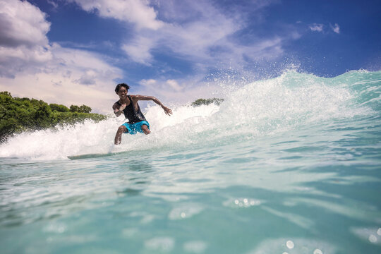 Low angle view of man surfing on sea against sky at Bali