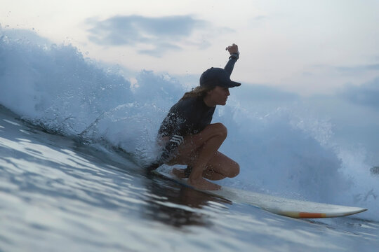 Woman surfing on sea against sky during sunset