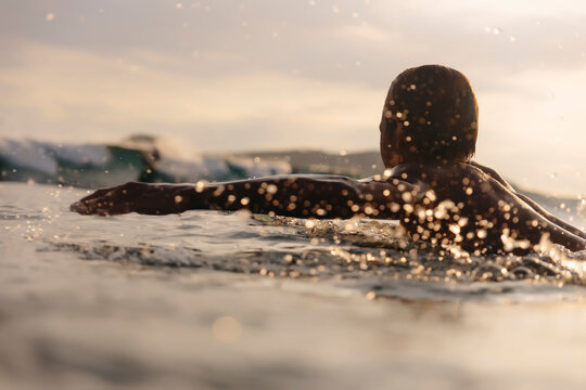 Man surfing on sea against cloudy sky during sunset