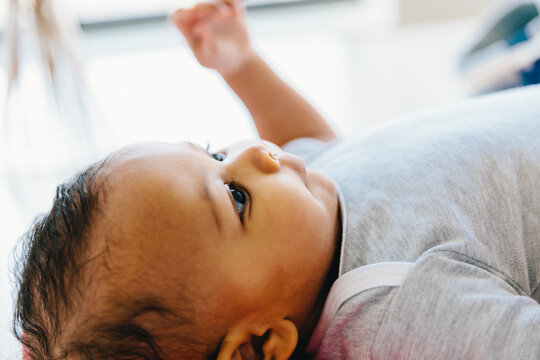 Close-up of baby boy looking away while lying on floor at home