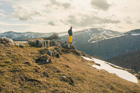 Full length of hiker looking at view while standing on rocks during winter