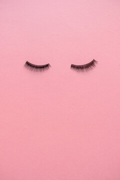 High angle view of false eyelashes on pink table