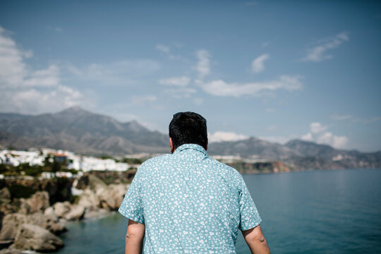 Man looking at view by sea against mountains and sky