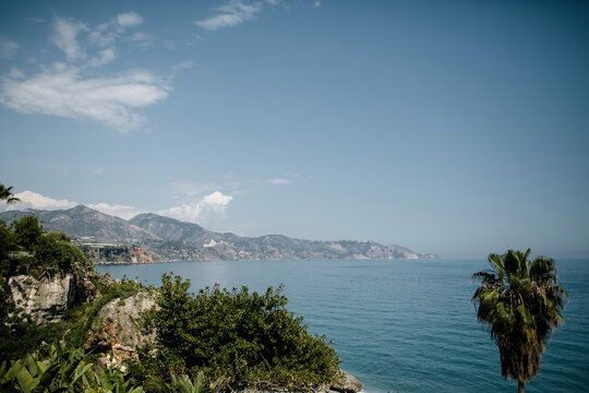 Idyllic view of sea by mountains against sky