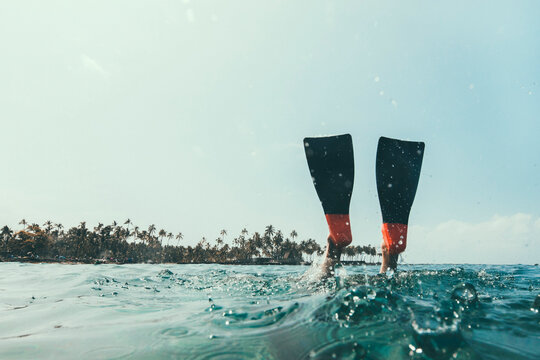 Low section of woman swimming in sea against sky during sunny day