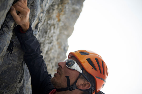 Hiker wearing helmet while climbing mountain against clear sky