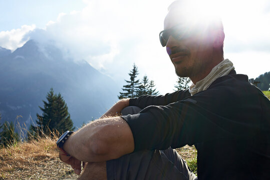 Side view of hiker sitting on field during sunny day