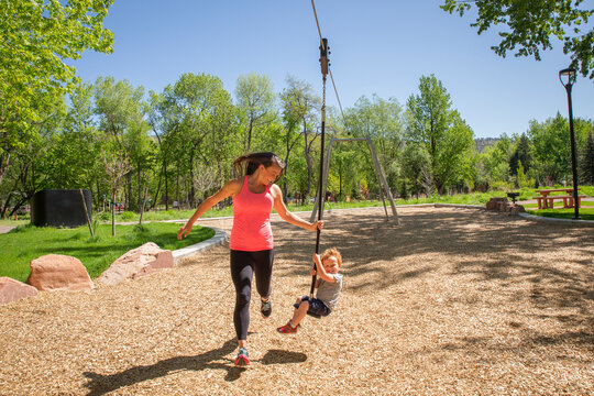 Full length of mother pulling zip line with son while playing at playground during summer