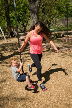 Full length of mother pulling zip line with son while playing at playground