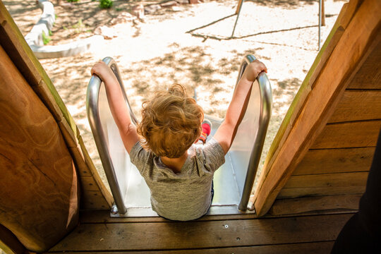 High angle view of boy sitting on slide at playground